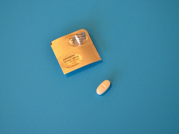 a foil packet of two yellow pills on a blue background