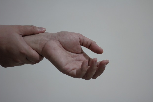 a person pressing their thumb into the wrist of their other hand)