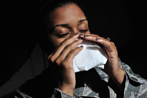 A woman sneezing into a tissue