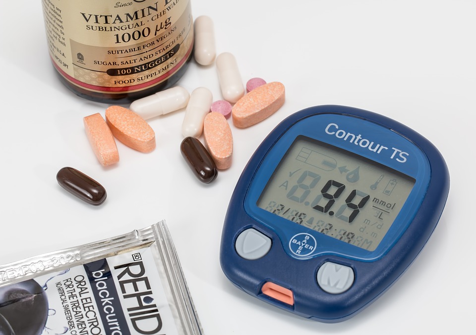 A blood sugar monitor and vitamins on a white background