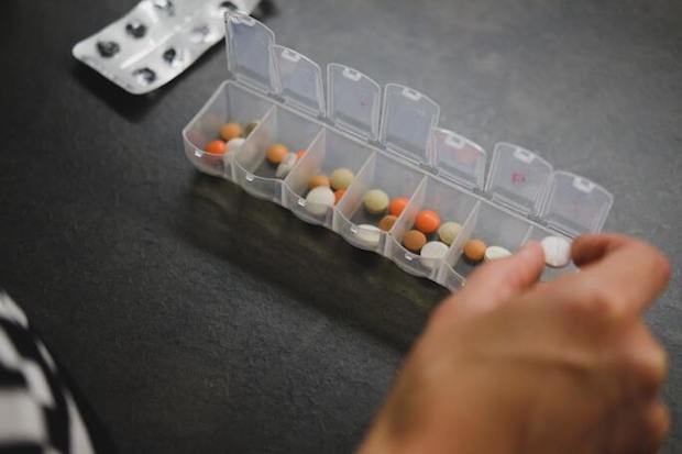 A hand sorting tablets into different sections of a container